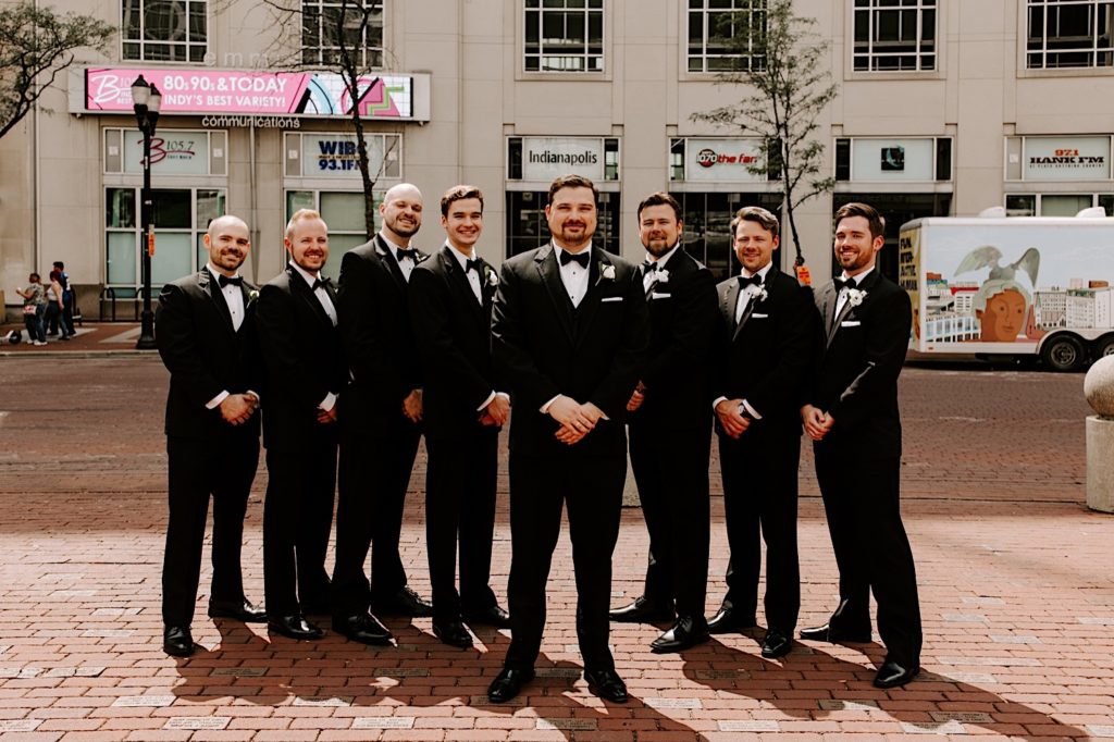 Groomsmen stand in Monument Circle Indianapolis posing together for a photo
