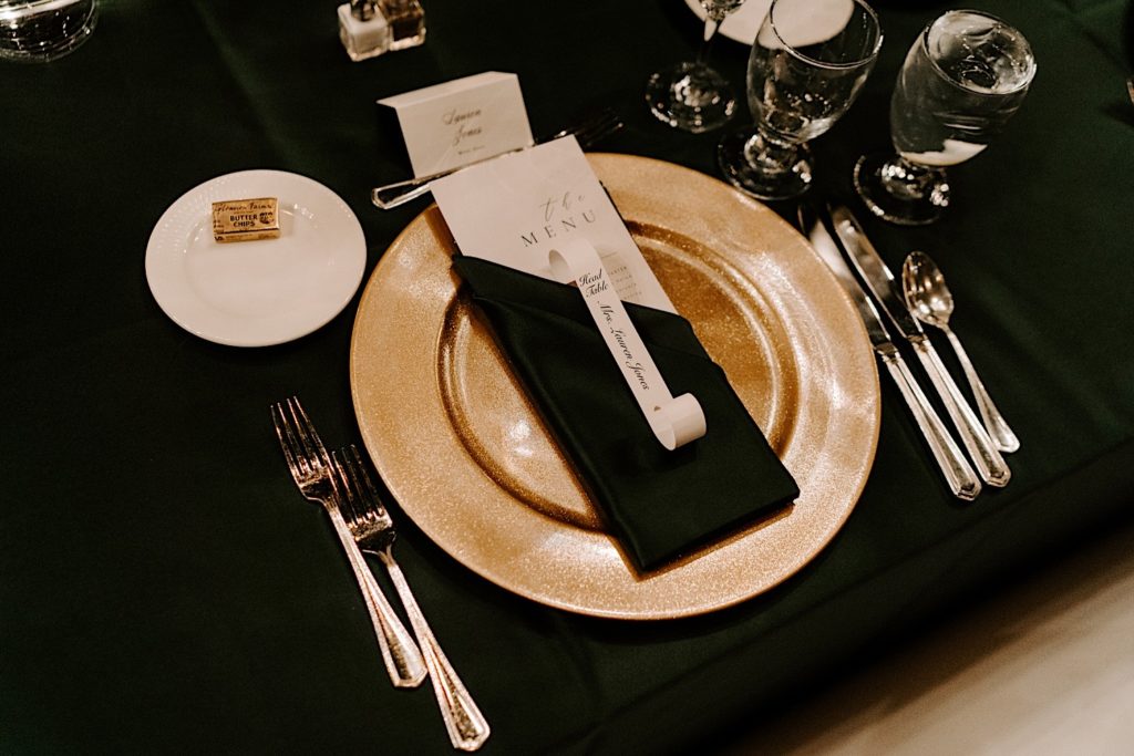 A look at the dinner menu on a gold charger before a wedding reception at the Indiana Roof Ballroom wedding venue.