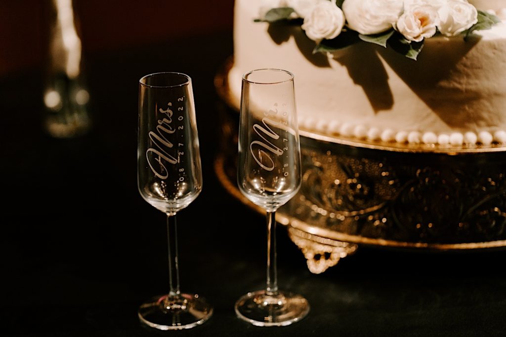 Customized Mr and Mrs champagne glasses sitting next to a wedding cake.