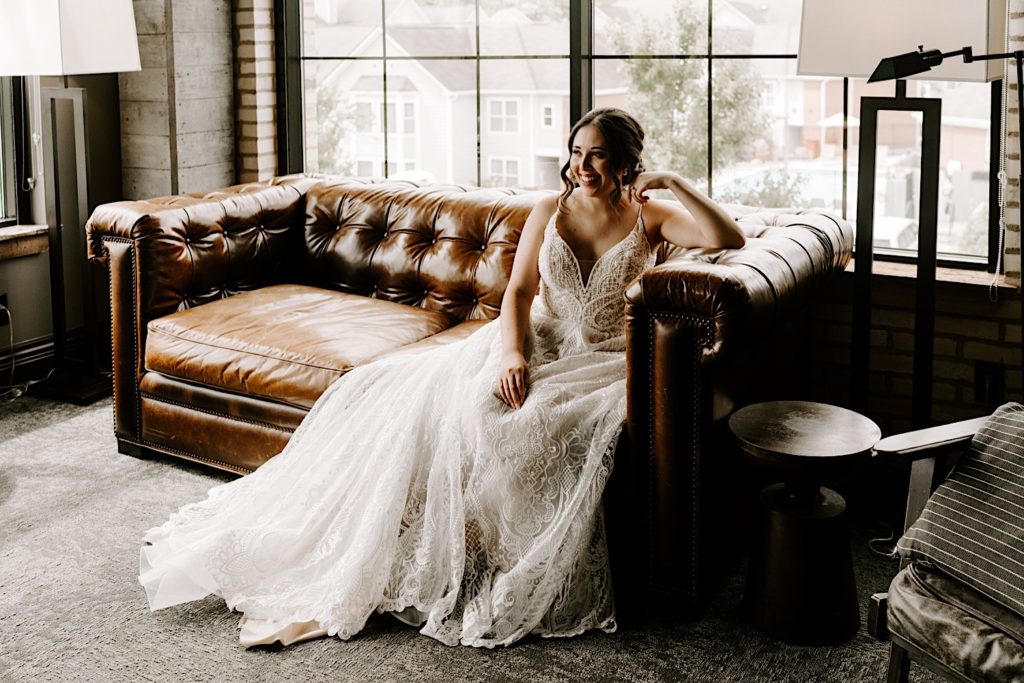 Bride sitting on a leather couch in her getting ready space at her Chicago wedding venue.