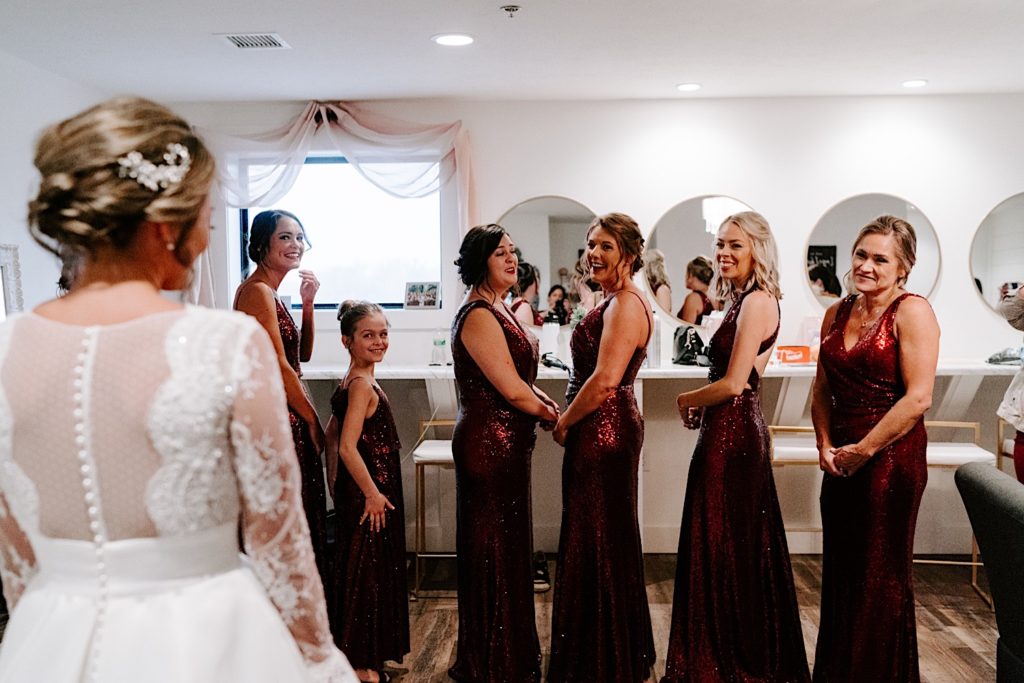 Bridesmaids in red dresses do a first look with their bride at their Chicago wedding venue.