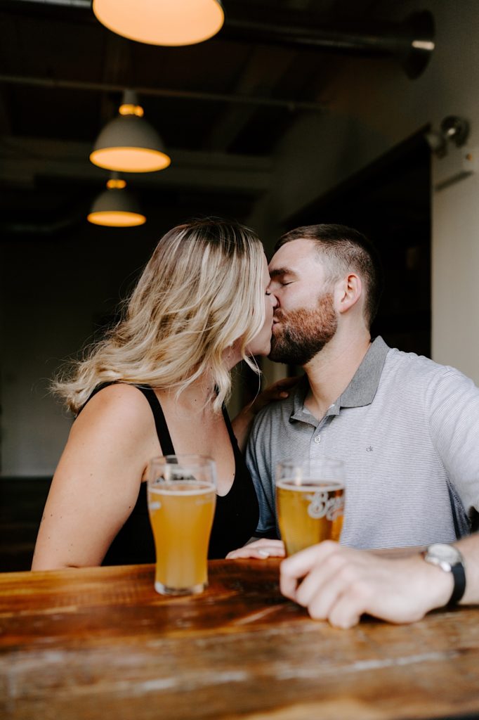 A couple kisses during their engagement session at a Ravenswood brewery in Chicago