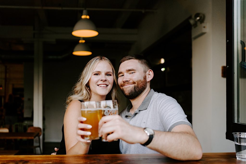 A couple cheers with their beers at a Chicago bar in Ravenswood