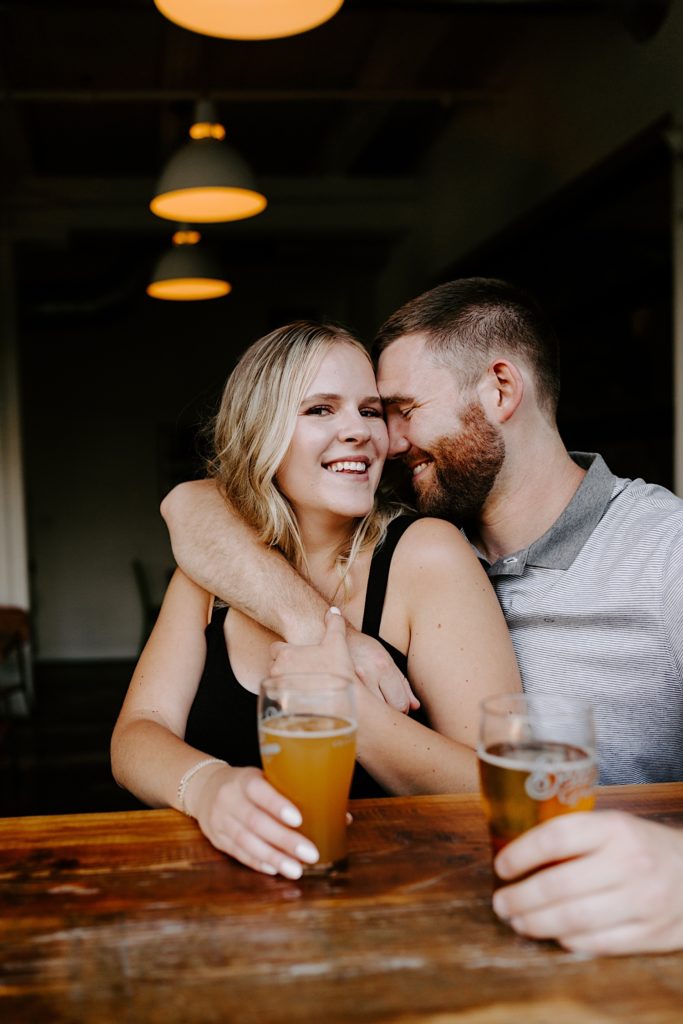Chicago sits at a Ravenswood bar smiling at the camera during their engagement session 