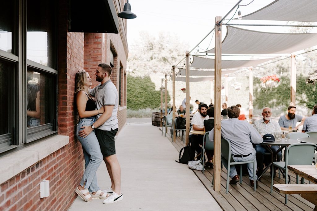 Couple stands against a brick wall and kisses at the Begyle Brewery in Ravenswood Chicago
