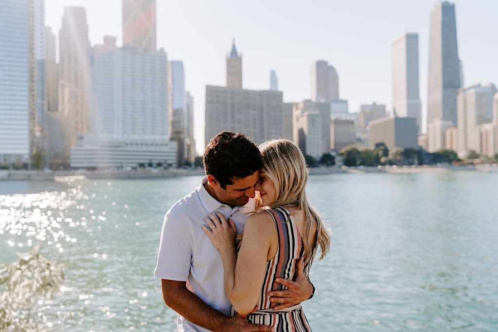 Fiancés snuggle in tight and hug on the lake front in Chicago during their engagement session at Milton Lee Olive Park