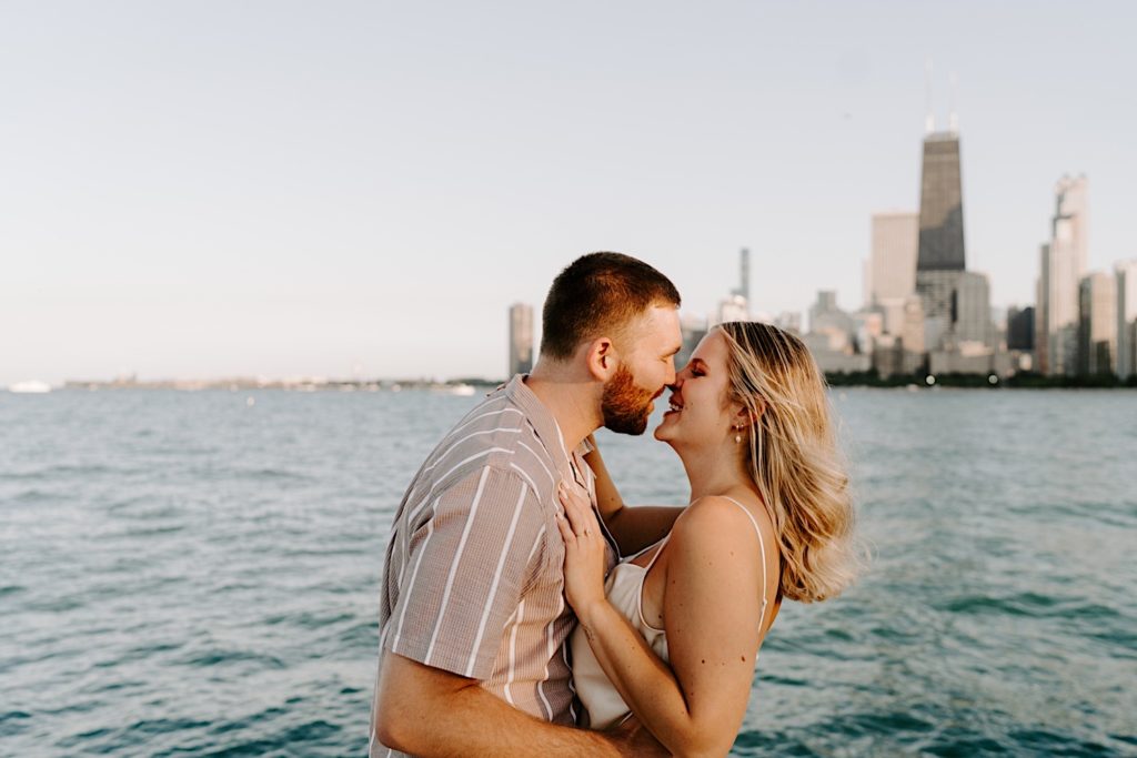 An engaged couple almost kisses during golden hour at North Avenue Beach in Chicago.