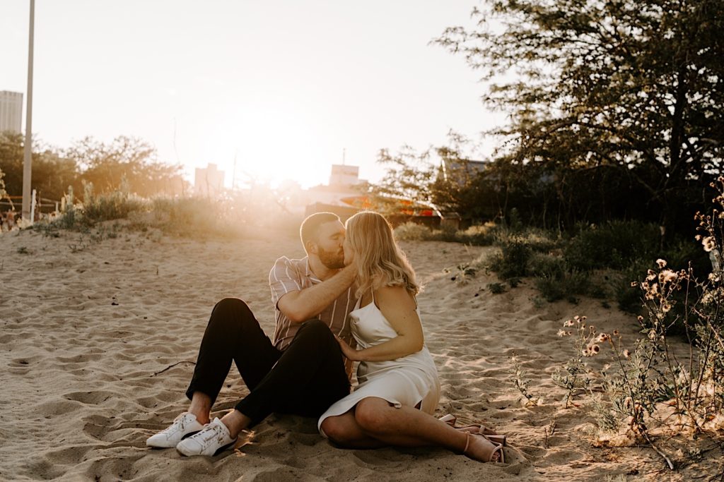 A couples snuggles on the beach during golden hour in Chicago