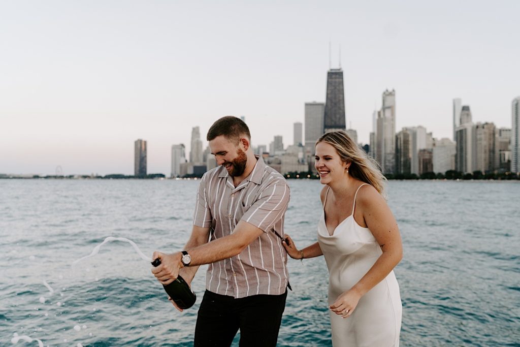 An engaged couple pops champagne at North Avenue Beach during their engagement session.
