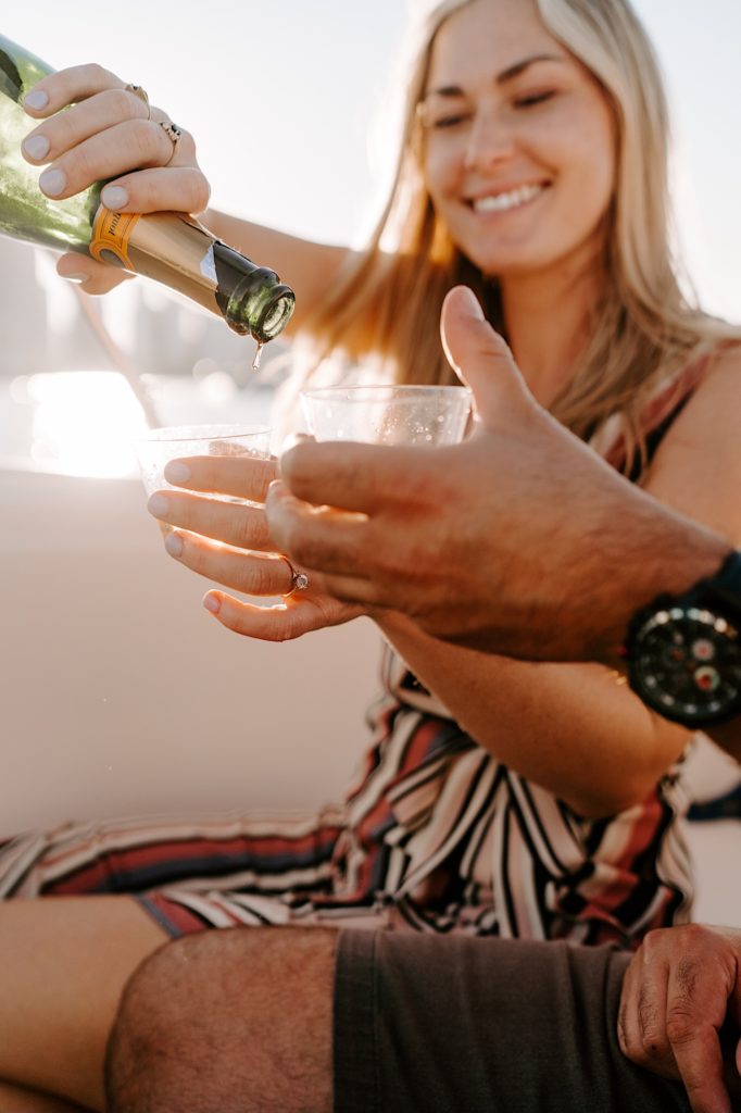 Fiancés pour champagne on a boat out on lake Michigan celebrating their engagement