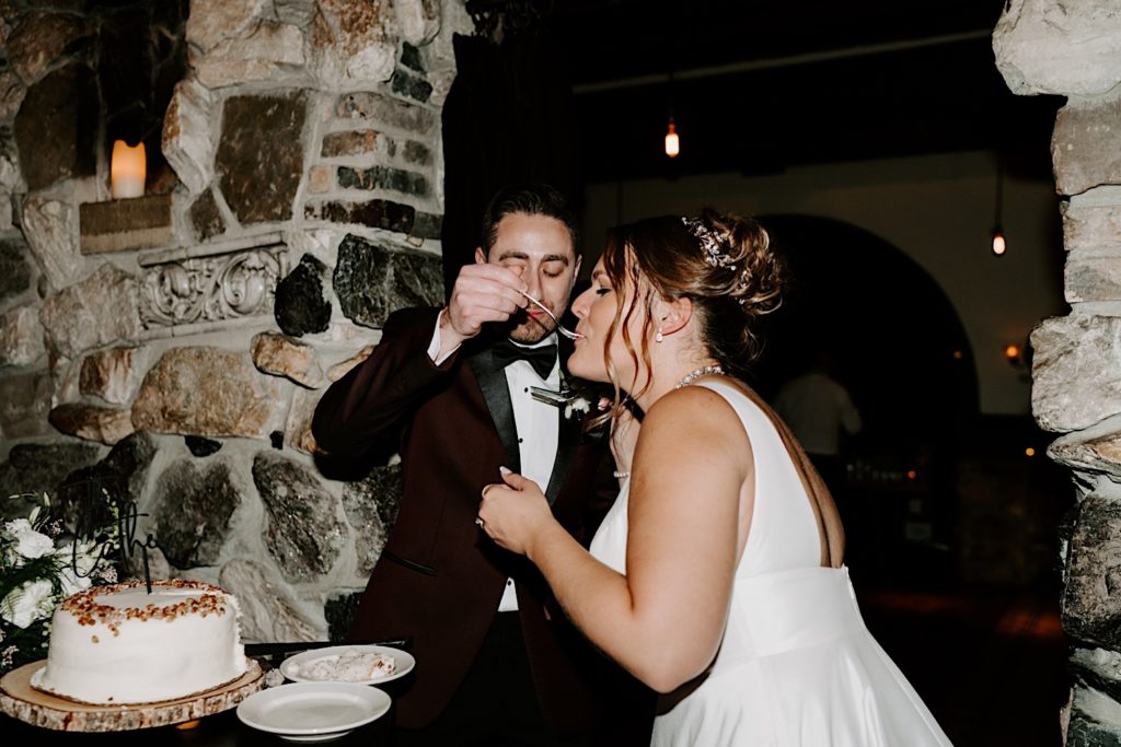 A bride and groom feed each other wedding cake inside their historic wedding venue in Geneva Illinois