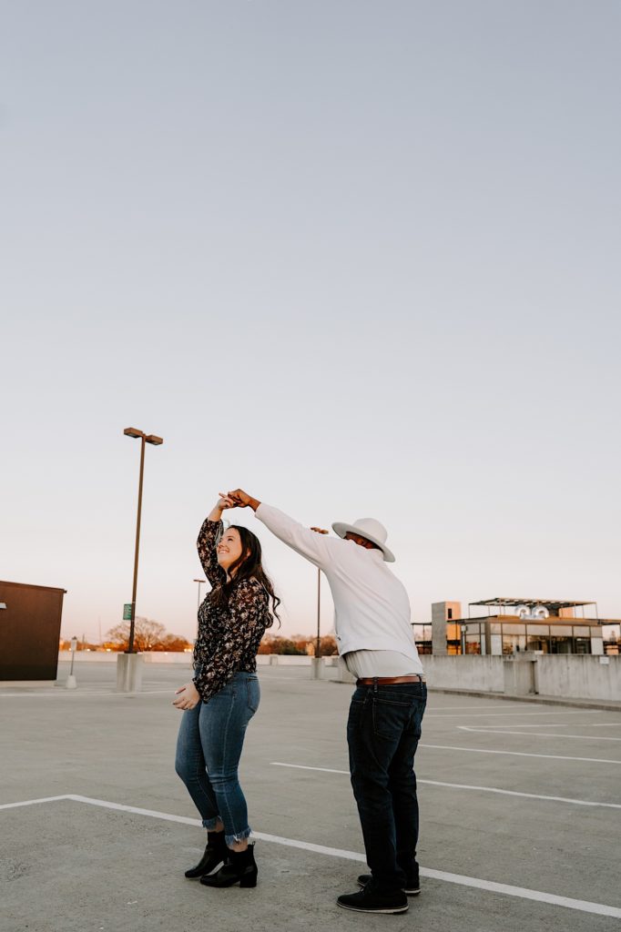 A couple dances on top of a parking garage after proposing during their engagement session.