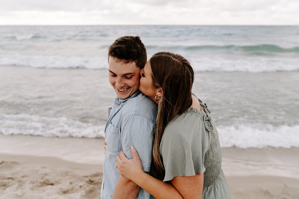 A couple kisses on the beach at lake Michigan in Chicago during their engagement session.