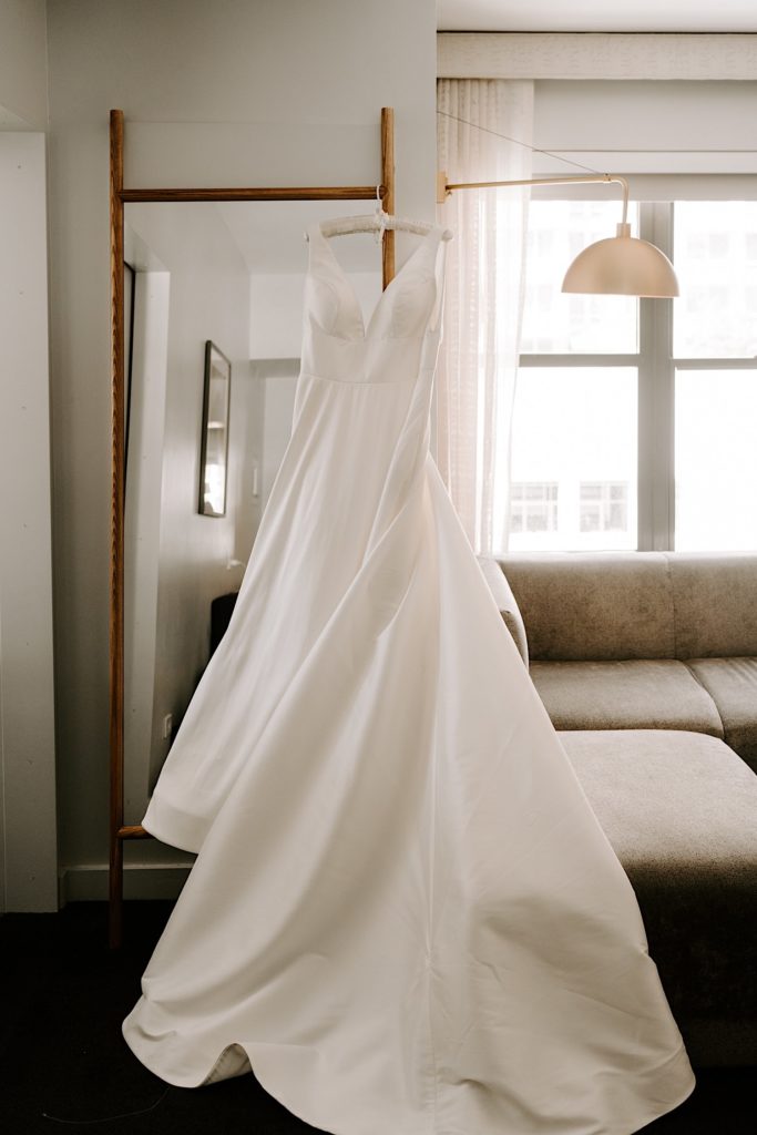 A classic white wedding dress on a silk hanger hanging from a mirror in a Chicago hotel.