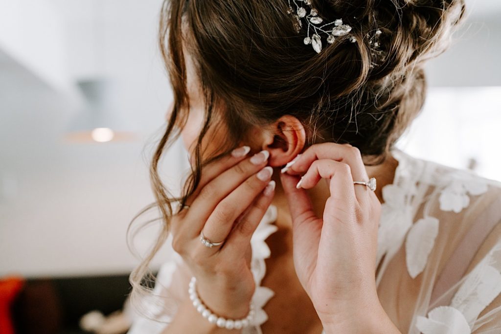 A bride puts in her pearl earrings on her wedding day.
