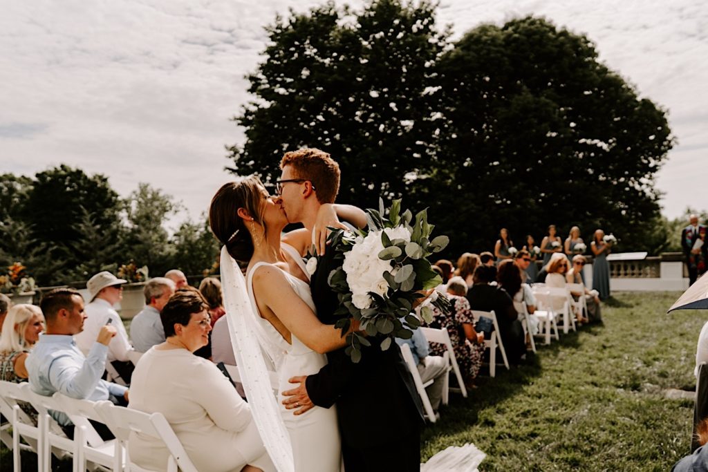 A couple kisses during their wedding recessional at their outdoor wedding in Chicago.