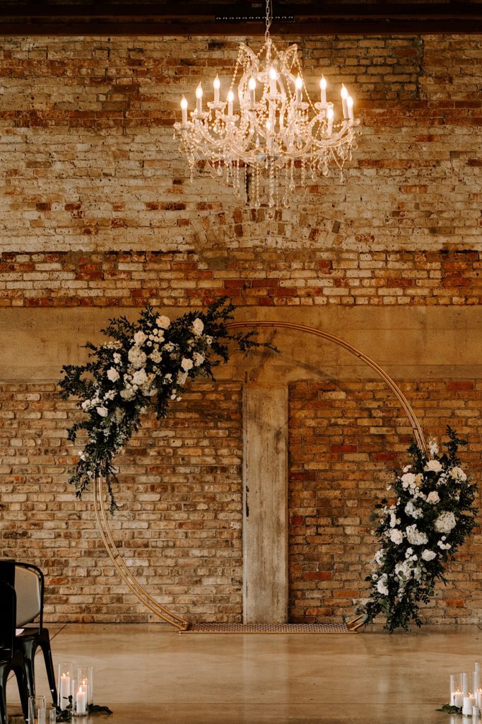 A wedding day arch with white flowers in front of a brick wall at a wedding venue in Chicago.