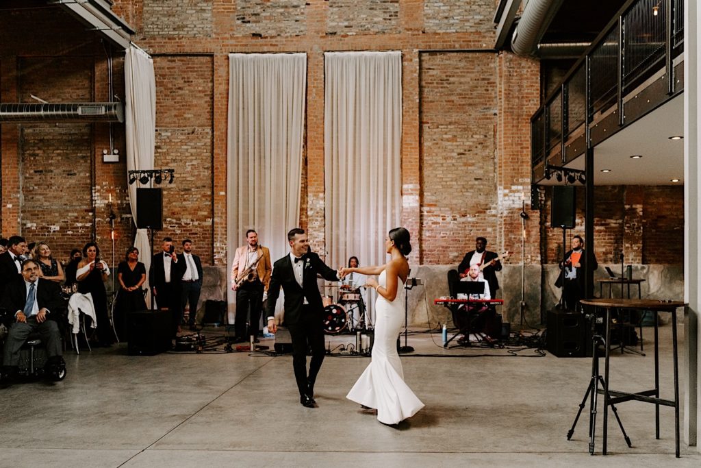 A couple dances in front of their wedding band at their urban loft wedding venue in Chicago