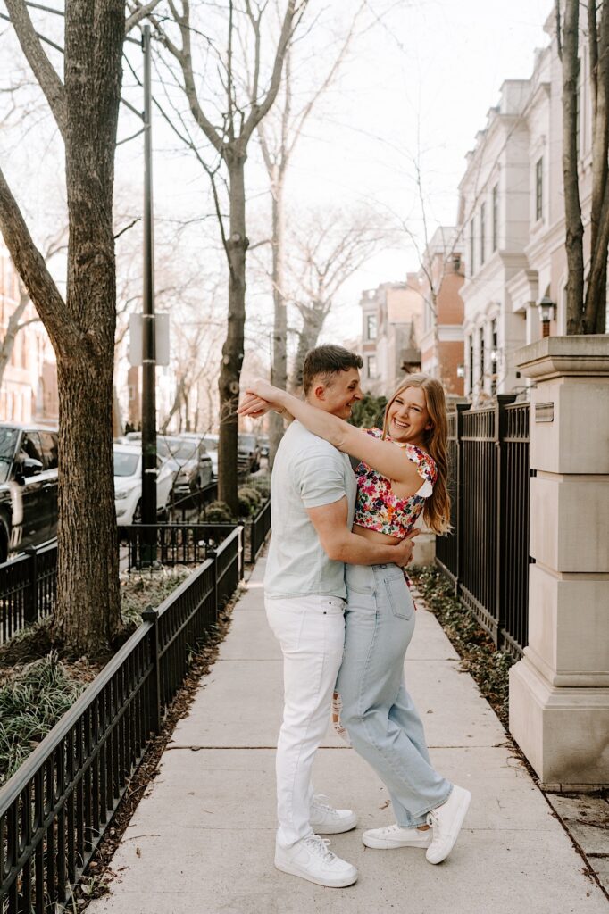 A couple embrace and smile with one another while on the sidewalk in the springtime in Chicago