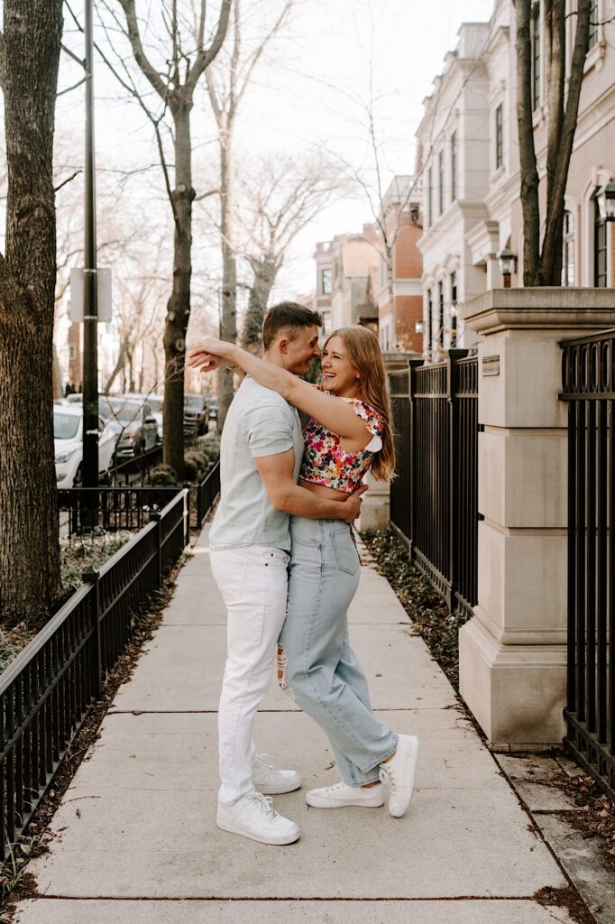 A couple embrace and smile with one another while on the sidewalk in the springtime in Chicago