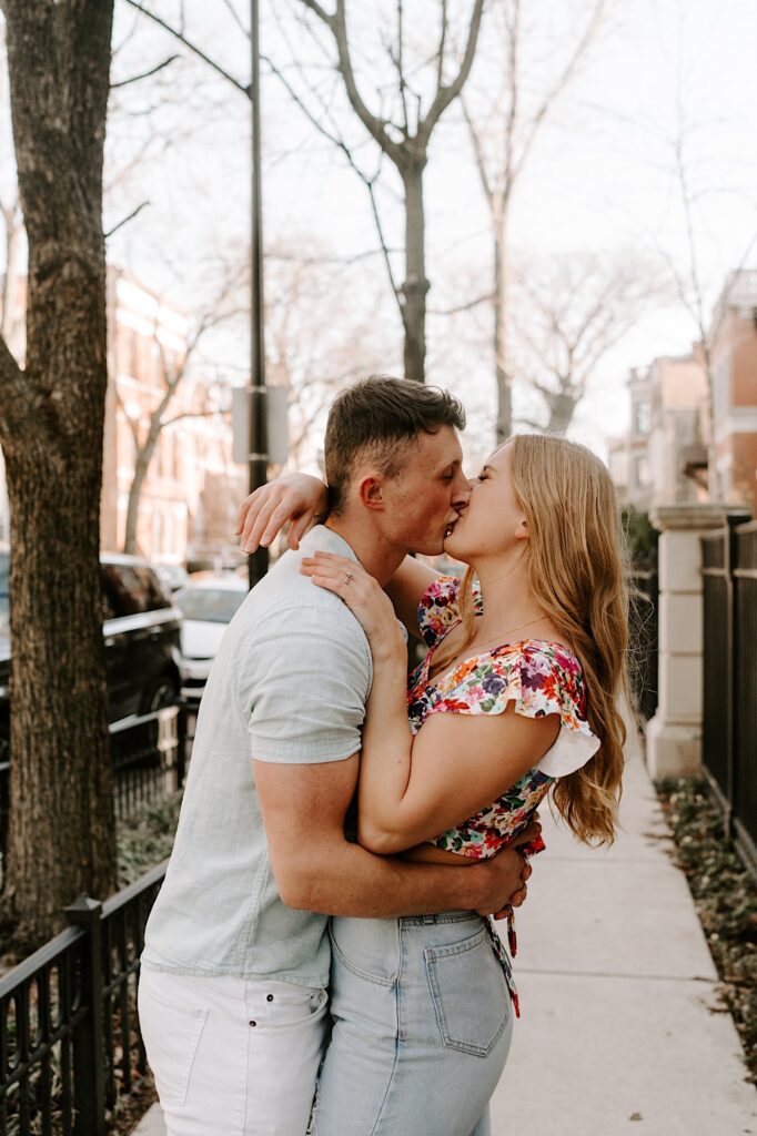 A couple kiss and embrace while standing on the sidewalk in Chicago in the springtime