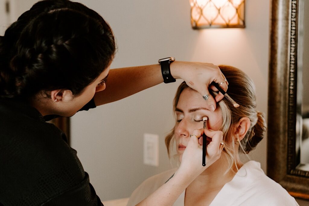 A bride has her makeup applied before her wedding day.