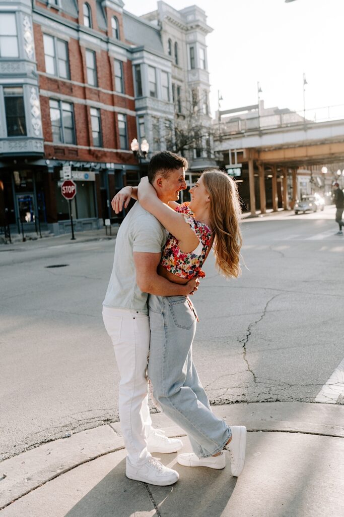 A couple embrace and smile at one another on the corner of a street in Chicago