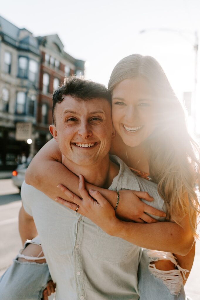 A woman rides piggyback with a man in Chicago as they both smile at the camera