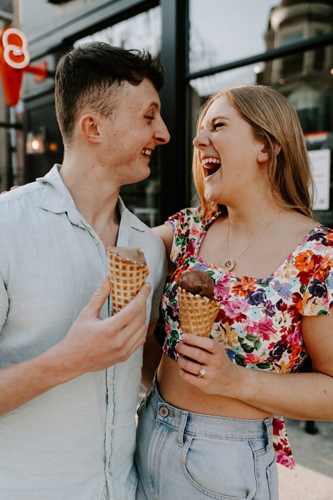 A couple laugh at one another as they hold ice cream cones