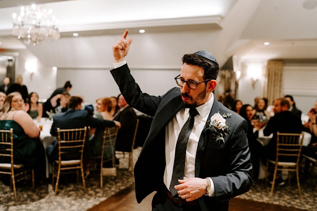 A groom points his finger in the air during his wedding reception at Barrington's White House