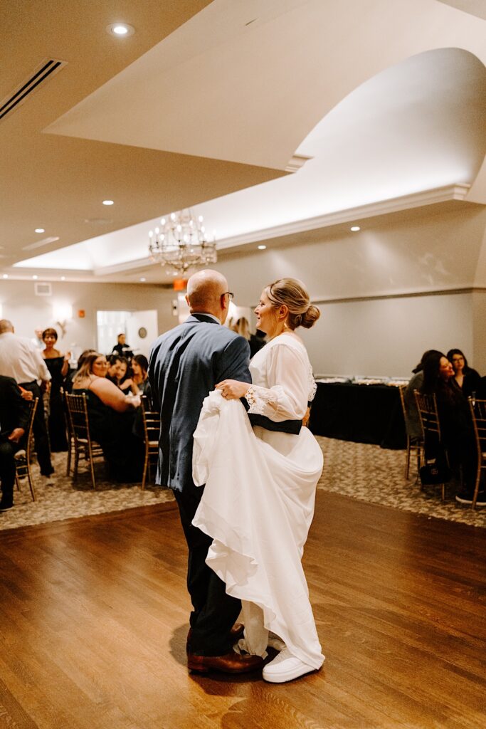 A bride and her father share their first dance together at her wedding reception.