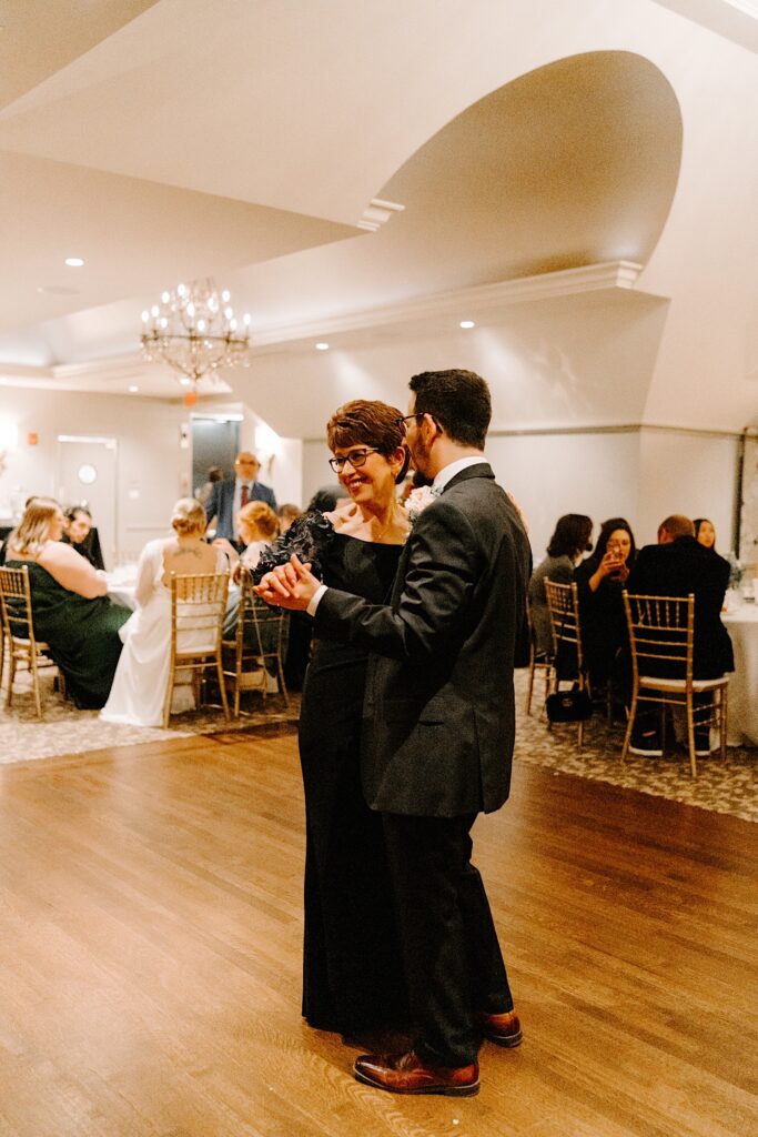 A groom and his mother share their first dance together at his wedding reception.