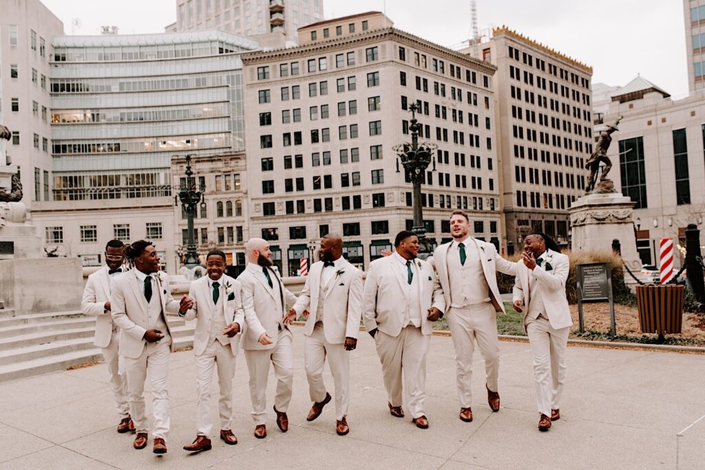 A groom and his groomsmen walk and talk with each other towards the camera in the middle of a downtown, photographed by a Chicago wedding photographer