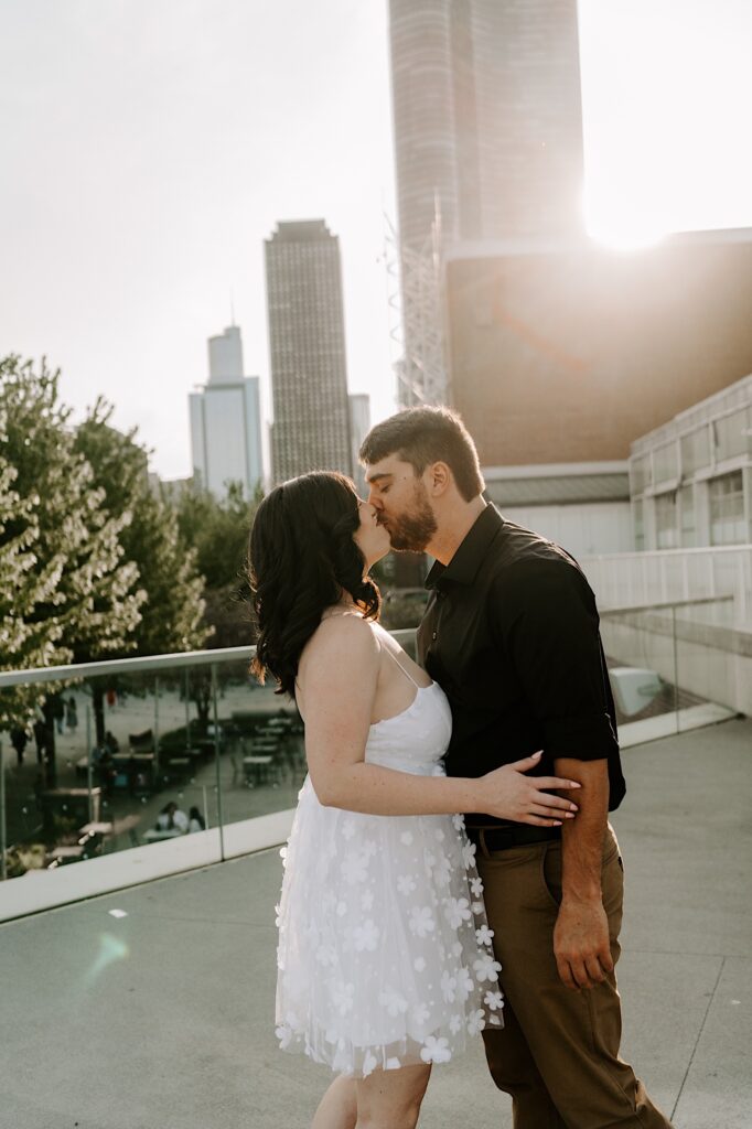 A couple kiss at Navy Pier in Chicago as the sun sets on the skyline behind them
