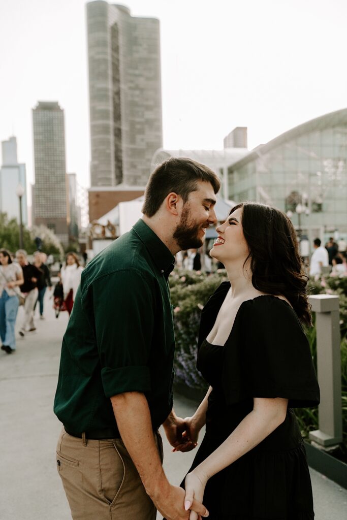 A couple smile as they're about to kiss while standing at Chicago's Navy Pier