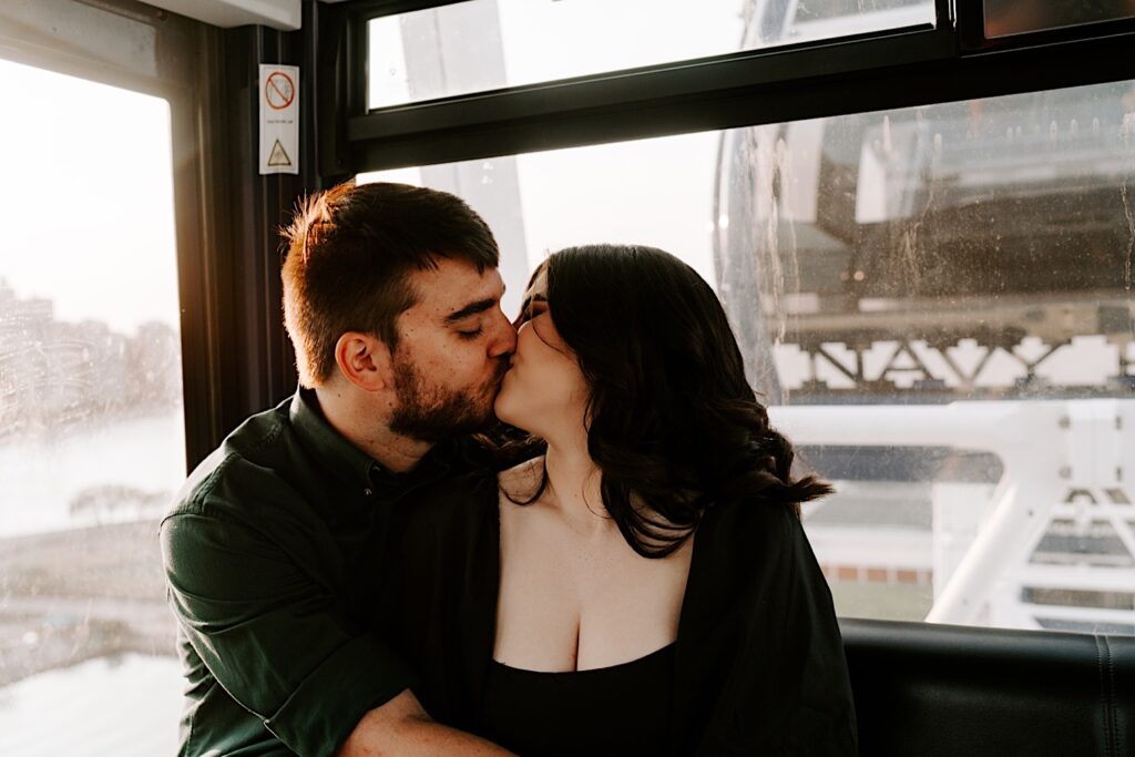 A couple embrace and kiss one another while riding the Ferris Wheel at Navy Pier in Chicago during their engagement session