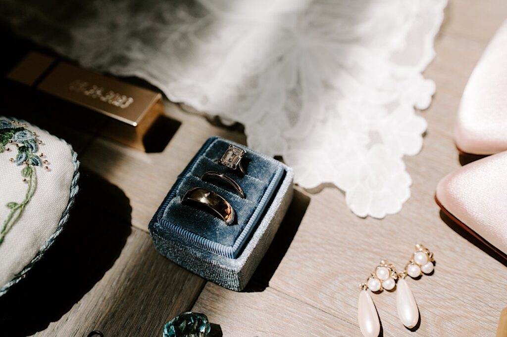 Detail photo of a wedding flatlay consisting pf wedding rings. earrings, and other items mostly out of frame