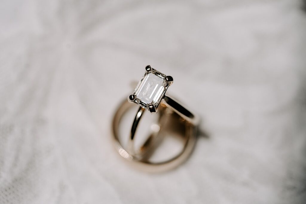 Detail photo of a wedding ring on top of other rings with a white background