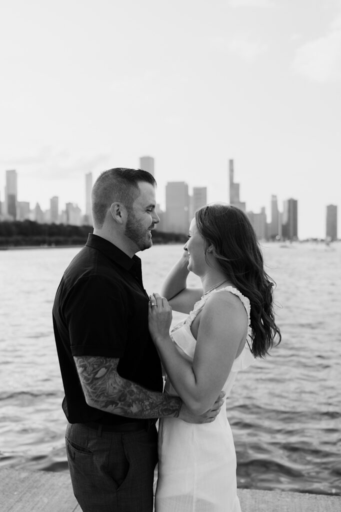 Black and white photo of a couple standing together in front of Lake Michigan and the Chicago skyline