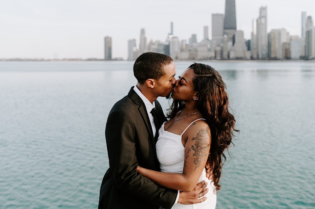 A bride and groom kiss with Lake Michigan and the Chicago skyline behind them