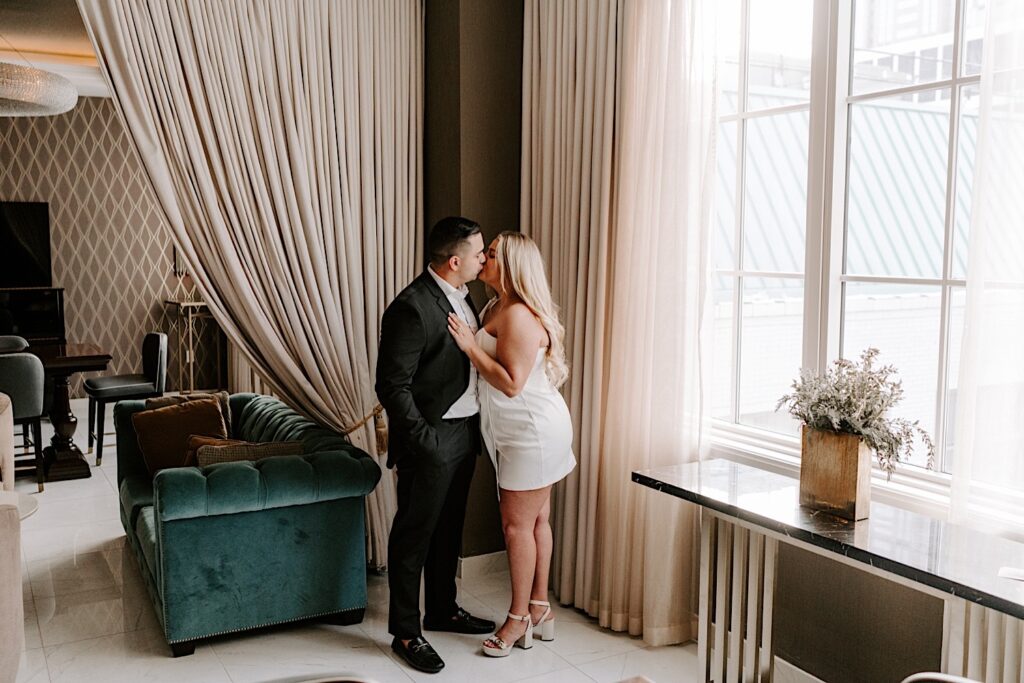 A man and woman kiss indoors at a luxurious hotel room in Chicago while taking their engagement photos