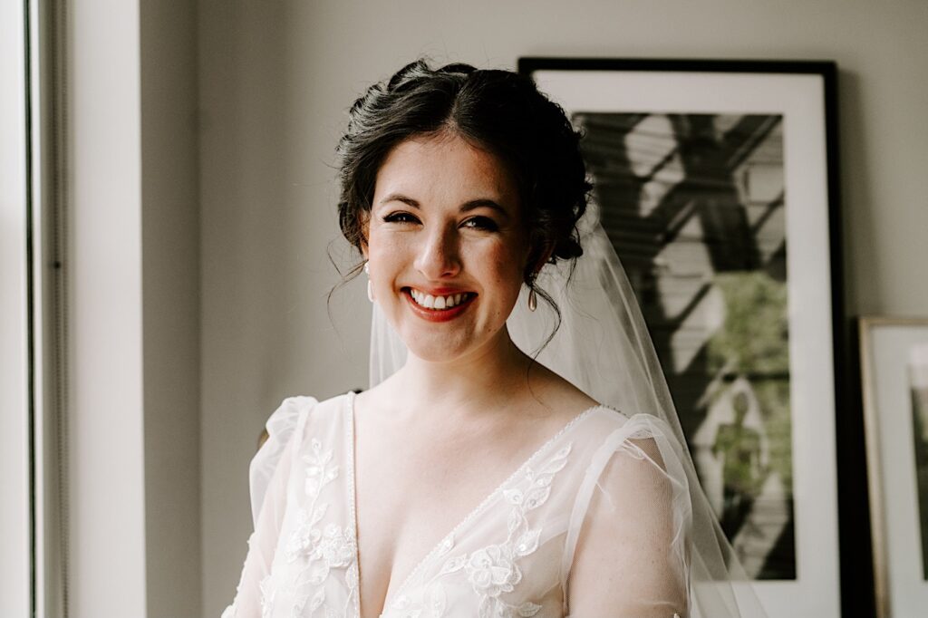 A bride in her wedding dress smiles at the camera for a portrait photo