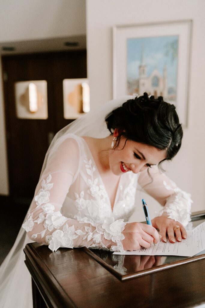 A bride smiles as she signs her wedding papers after her wedding ceremony