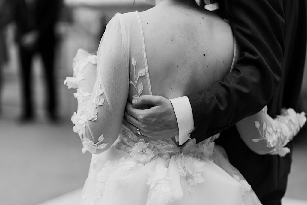 Black and white photo of a bride being held by the groom in their wedding attire