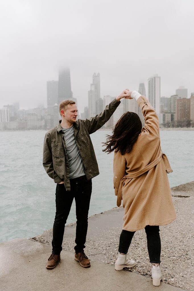 A man and woman dance together on the shore of Lake Michigan with the Chicago skyline behind them