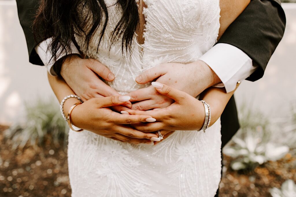 Close up photo of a groom's hands holding a bride as she places her hands over his