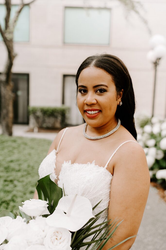 Portrait photo of a bride smiling at the camera while standing in a courtyard
