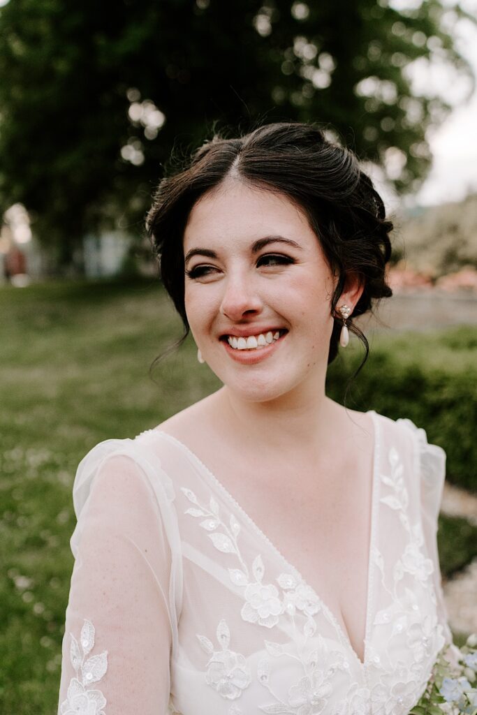 Portrait photo of a bride smiling to something off camera while standing in a park