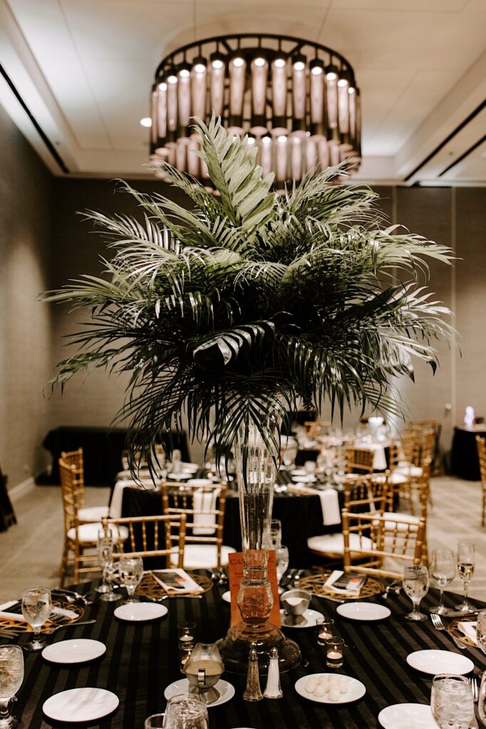 A large plant sits in a vase on a table decorated for a wedding reception