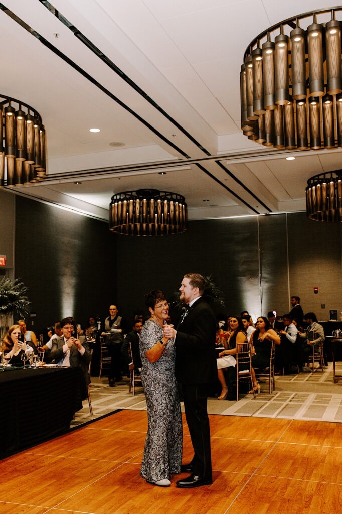 A groom dances with his mother during the indoor reception of his wedding